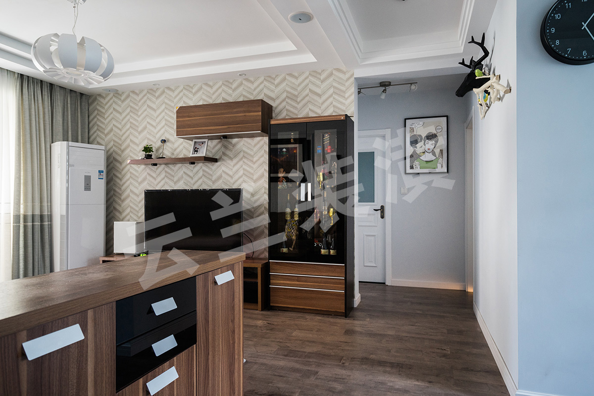  現代人們越來越喜歡簡單化的家具，它舒適更便于打掃，所以客廳的家具雖保持著美式的沉穩顏色，但是沒有了繁瑣的花紋和配飾。那更多美式的元素就是藏在與吊頂和立面簡單的畫框線條。他的吊頂更多的是層層疊加，讓整個立面看上去更立體。再配上客戶花心思淘的配飾和掛畫，讓整個空間一下子生動了起來。客廳的整個立面設計都已經簡單化，已有了沙發背景的線條框，所以電視背景只采用了簡單的墻紙來修飾在配上組合柜來豐富整個格局。最后加上顏色亮麗的掛畫和抱枕讓整體空間都生機勃勃了起來。
