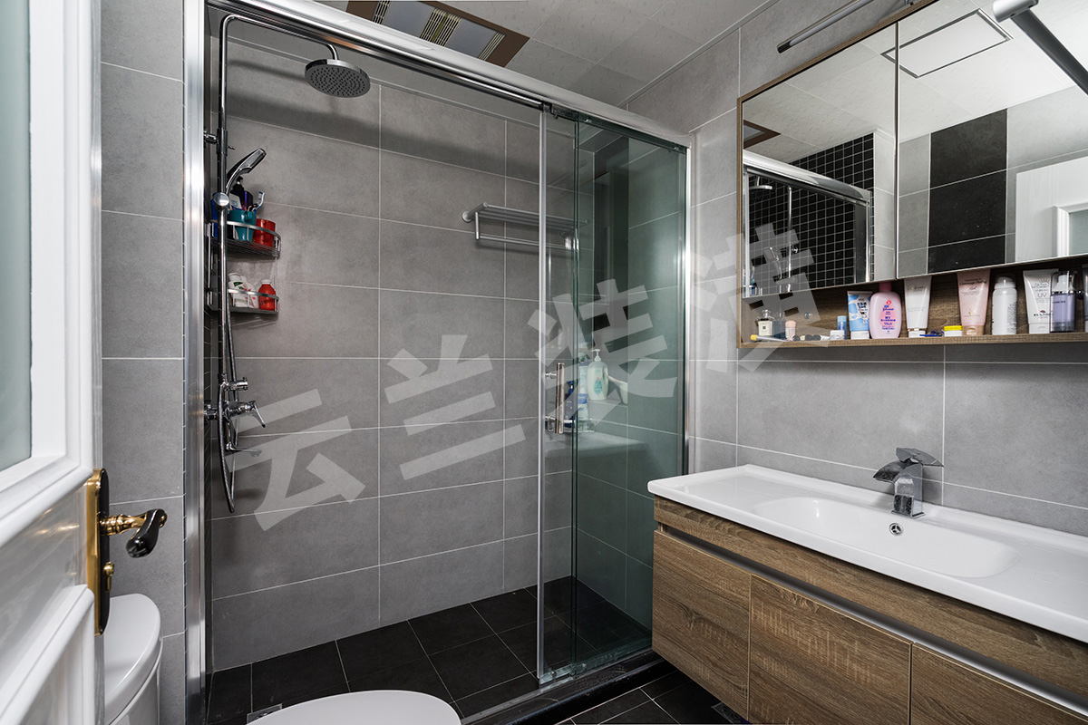 衛生間干凈明亮，主色調采用淡淡的灰色，但是又不想過于單調，所以在掛花灑那面墻面采用了深色馬賽克，還有在馬桶背后也采用深色面磚加于修飾。
