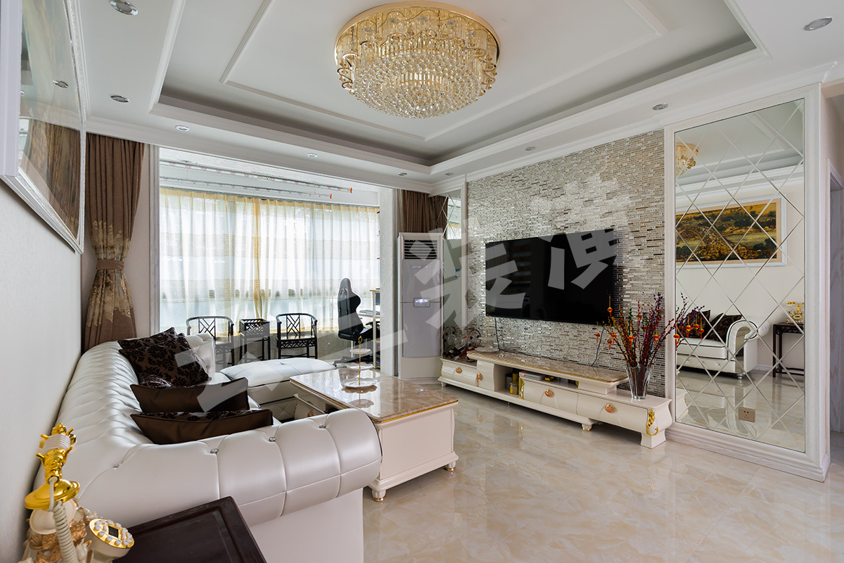 客廳為了襯托歐式的淺色家具，客廳采有光潔淺色的地磚，使得整體協調，也更凸顯了家具的質感，品質生活油然而生。歐式家具低調而奢華，充分體現了業主的，低調而內斂的做人風格。電視背景墻的線框采用的實木線條，中間采用的是當下比較流行的馬賽克，兩邊菱形抽邊境，顯得清新大氣。
