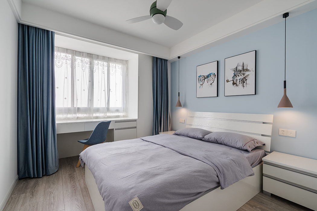  臥室爽朗大氣的線條勾勒出干練的個性氣息，為了不打破安逸舒適的空間感，陶瓷色的床頭燈與藍灰色的布藝窗簾恰到好處的降低空間過于高調活躍的色彩基調，同時襯托富有質感的裝飾畫，淺紫色軟麻布床單搭配出豐富的層次感，傳遞專屬現代主義的奢華、溫馨、向往自由的風格，舒緩了人的緊張心情，讓人坦然釋放，回歸自我。
