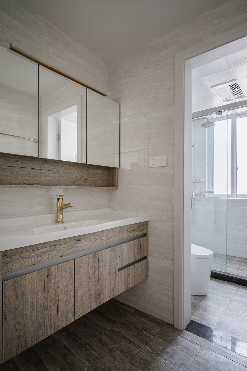 衛生間，則是簡單的材質對比，襯托出每種材質特有的性格和溫度。如原木色的臺盆柜、半透明的不銹鋼夾絲玻璃，都有它們特有的屬性。干濕區的過渡也不會對采光造成影響。值得一體的是臺盆柜上方的鏡前燈，簡潔明了，臺盆柜下端的這部分空間更是合情合理的考慮了衛生的清理。
