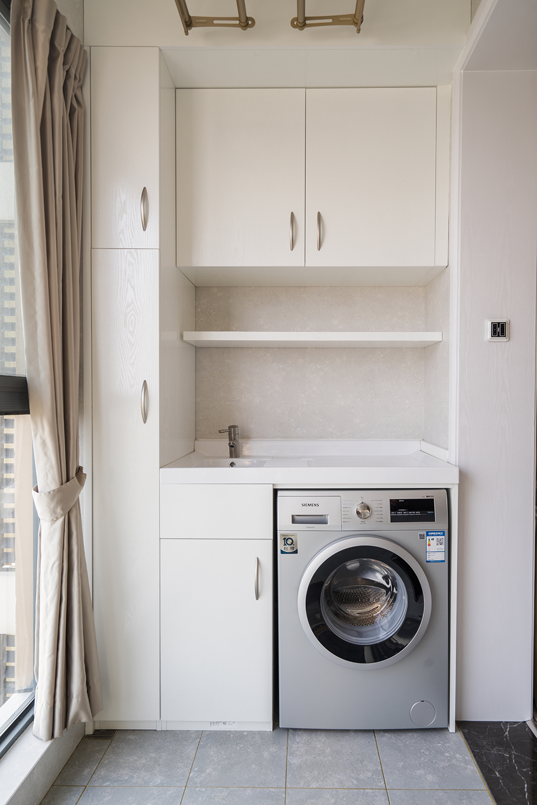 而本案空間采用原木色系的色調，主空間靜謐藍的沙發背景和紋理清晰的木飾面電視背景相互呼應。同時靜謐藍的背景襯托了淡灰色輕奢的布藝家具及軟裝畫，讓空間不在拘謹，在陶瓷白的茶幾的對比下產生色彩的碰撞，造型簡潔的家具設計透露出幾分優雅怡然的空間氣質。
