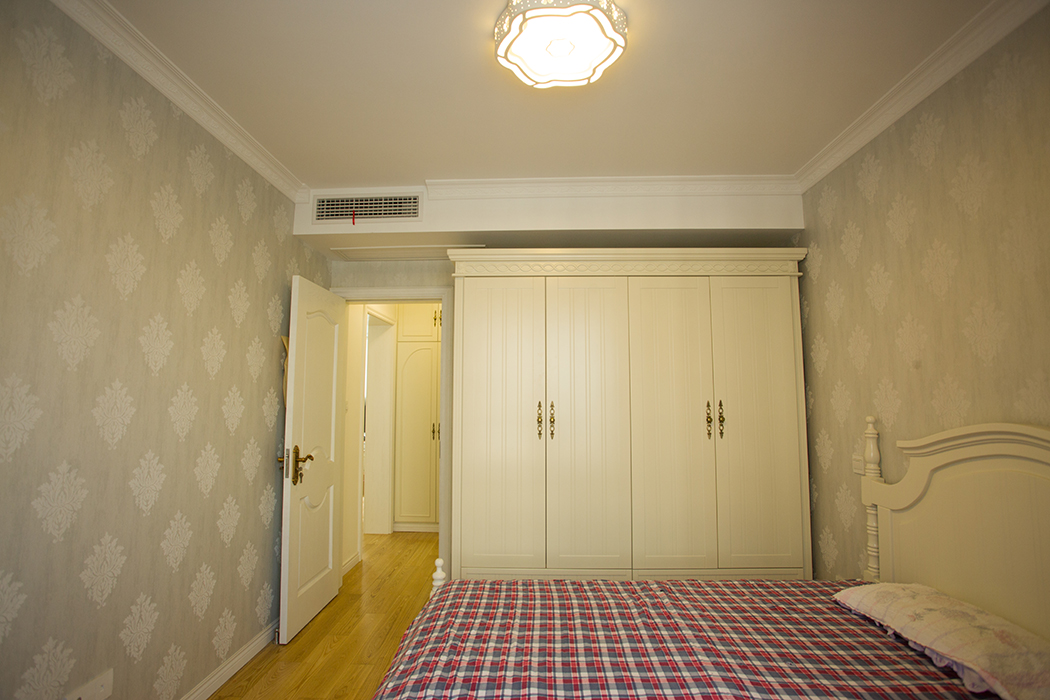 主臥室墻面貼的是淺灰色無紡布，搭配象牙白的整體家具，主臥朝南，陽光照進臥室顯得格外溫馨。
