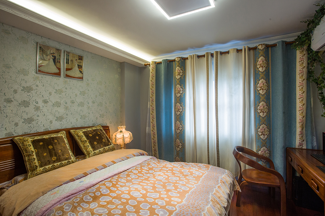 主臥室軟裝部分選用了當(dāng)下流行的冷色系，淺綠色小碎花墻布和天藍(lán)色窗簾搭配起來相得益彰，清新自然，舒適浪漫，身臨其中感覺煩惱都少了幾分，心情自然放松。