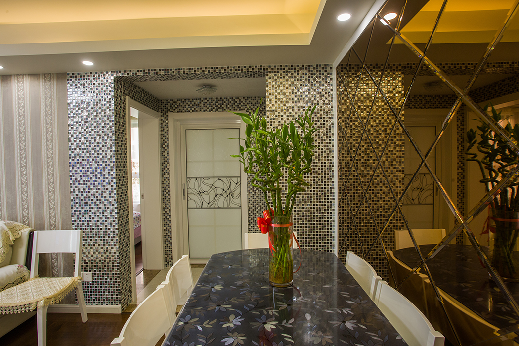 現代簡約風格餐廳裝修中，其木質的餐桌椅，給人一種賞心悅目的真實質感、溫暖的觸感以及最純粹的視覺觀。充滿紅色調點綴的原桌上放上一瓶綠色植物，預示著溫暖中孕育的生命，在春天的季節里茁壯成長。
