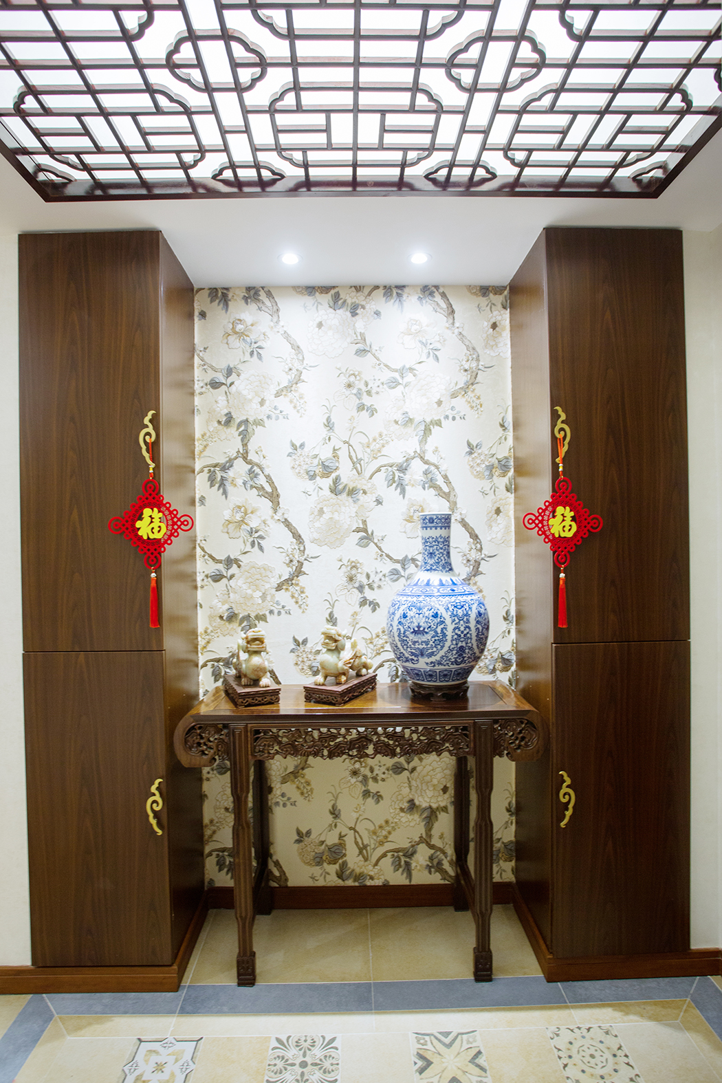推門而入，迎賓臺、玉器便映入眼簾。與古典的背景壁紙和鞋柜相互呼應。玄關空間更是巧妙銜接了餐廳，兩個空間，移步換景，不但有傳統的曲徑通幽，豁然開朗之感，又有自然大氣，不拘一格的禪風意境。
