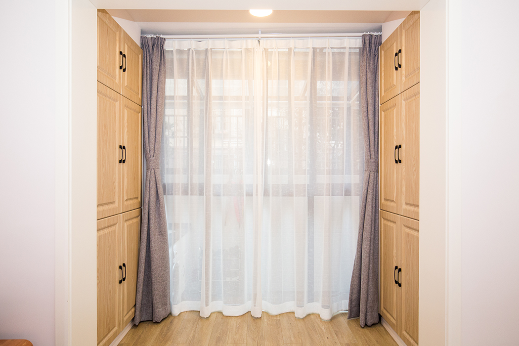 房間以原木色為主，落地玻璃可以讓陽光全曬進來，原本陽臺區(qū)域擴到房間，還增加了兩面儲物柜，房間以溫暖舒適為主。
