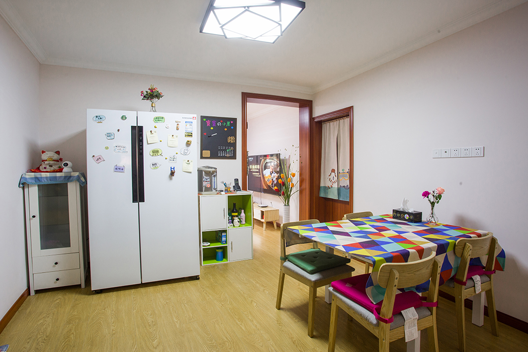 潔凈大方的餐廳空間，冰箱邊上的餐邊柜設計解決了收納難題，白色的雙開冰箱，北歐原木風格的餐桌加上亮色臺布削弱了中性色調帶來的距離感，烘托出溫暖親近的居家氛圍，打造別致的用餐環境。
