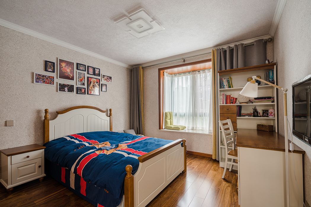 次臥還是征求了業主兒子的喜好，以現代偏英倫風格來裝飾，墻頂面都改用墻紙來打底和臥室客廳風格完全不同，但局部的深色家具很好的呼應了門套和窗套，讓區域和區域也融入一體。
