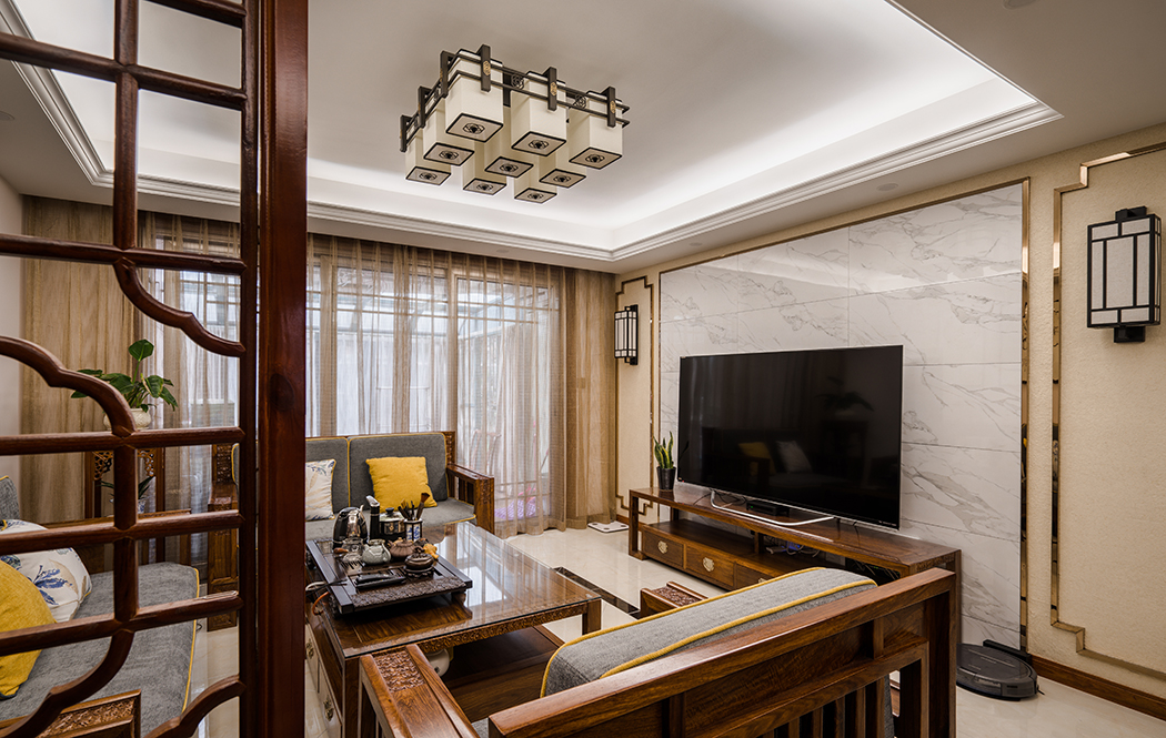 客廳整體風格采用大理石上墻和不銹鋼線條墻衣打底，這類元素增加了現代感，吊頂沒做過多修飾，簡單的吊頂增加了空間層次感，家具和軟裝又把我們帶入中式的元素里。
