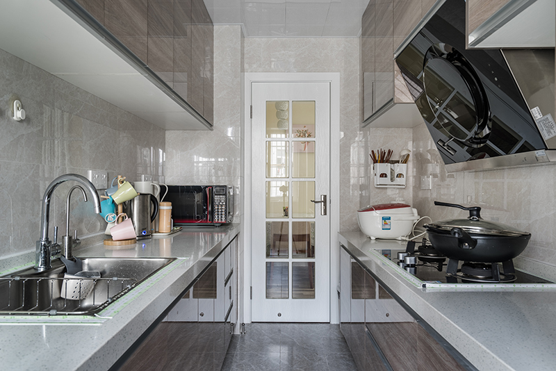 整體的廚房區(qū)域，墻磚還是一貫素雅，?；u空間給人很明亮，兩邊都做了操作臺面也不覺得壓抑，櫥柜又了亞克力的門板色調(diào)木紋色，不僅耐臟還很時尚。
