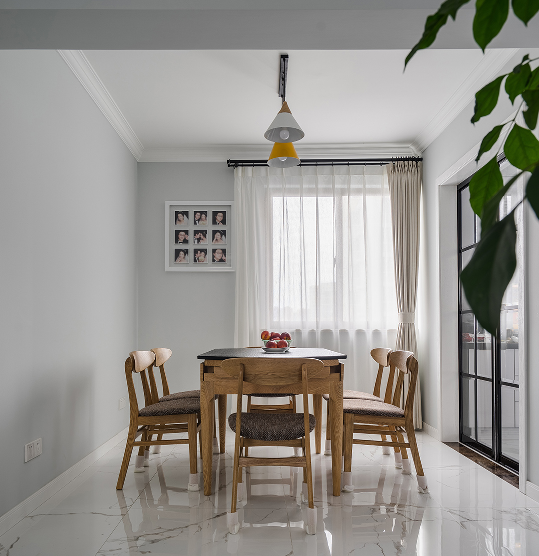 在餐廳的設(shè)計上，我們延續(xù)了客廳的灰調(diào)，明黃色餐廳燈給整個空間多了一絲明快，原木色的餐椅以及深色坐墊現(xiàn)代感分明，淺色窗簾元素中削減了空間的硬度。黑色格子玻璃門與餐廳風(fēng)格保持協(xié)調(diào)統(tǒng)一。
