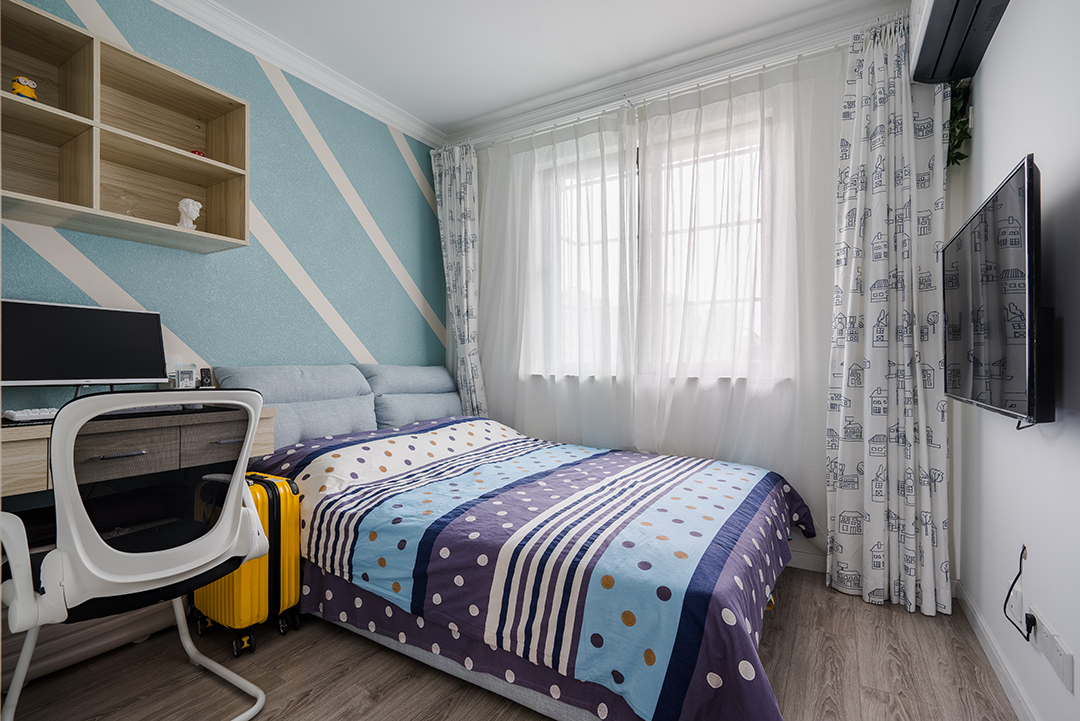 小孩房背景墻用幾何色塊打破單調(diào)氛圍，床品依舊是香芋色為主，圓點點綴。選用白色卡通圖案窗簾，增加了些許童真。
