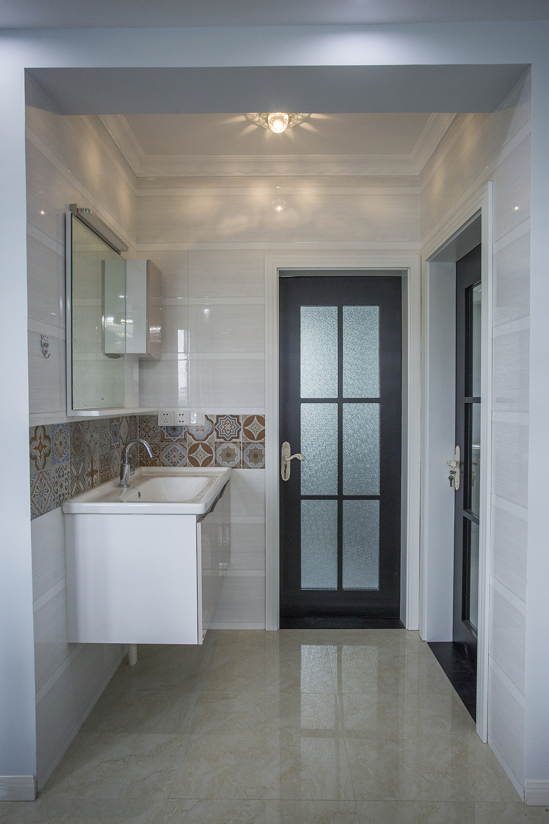 衛生間采用干濕分離，次臥門洞改到側邊，使衛生間多出一個放臺盆的位置，濕區也更寬松。掛壁式的臺盆和鏡柜之間的腰線作為點睛之筆，讓盥洗區也變得生動，
