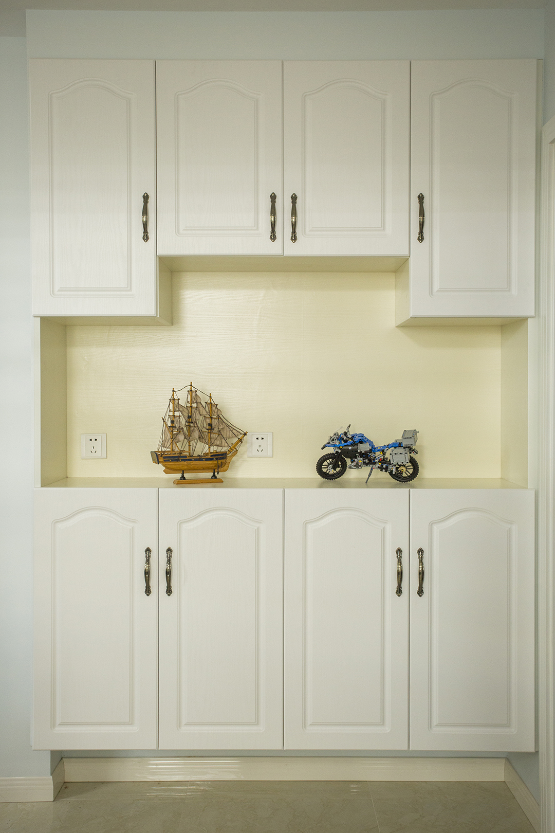 門口的鞋柜讓人一進門就被吸引住，白色模壓門板簡單大氣。底部騰空用來放拖鞋，讓辛苦一天的主人一回到家就馬上換上拖鞋，身體和神經才能放松。中間開放部分高低錯落，方便放包和鑰匙，也能放些裝飾擺件，讓這玄關不再千篇一律。