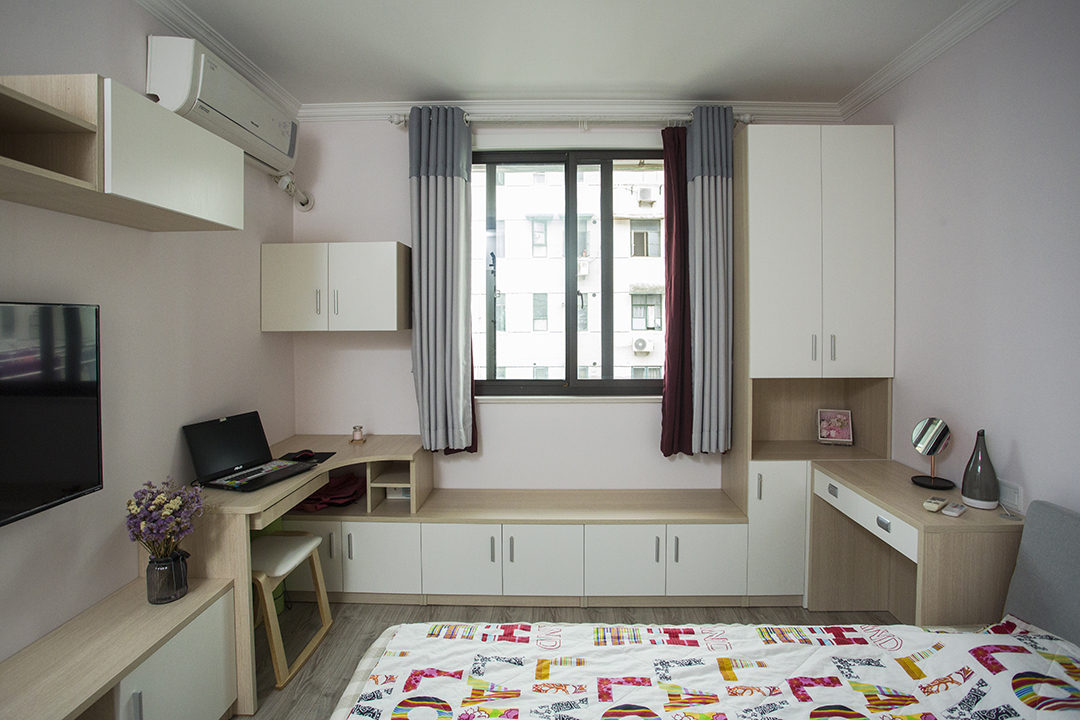 將電視柜與書桌以及窗邊休息座連為一體，在相對有限的空間內盡可能的豐富功能需求，以淺粉色作為空間的基調，輔以淺木紋、中性灰色適當點綴修飾，營造溫馨氛圍。
