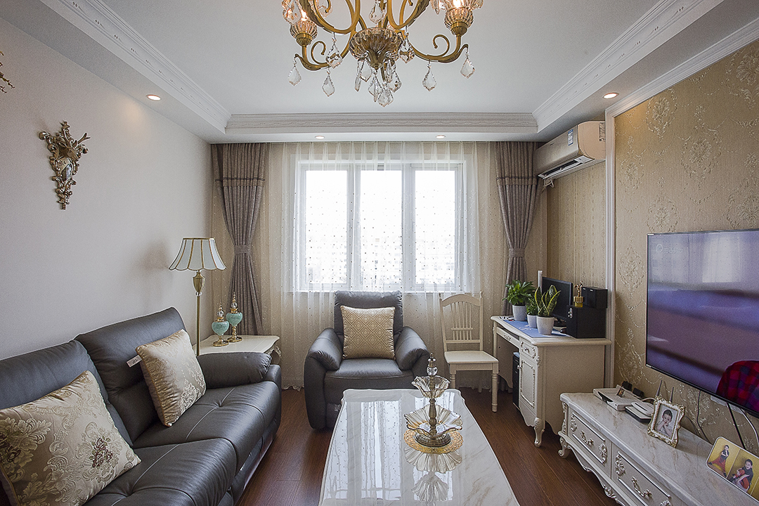 客廳采有光潔大氣的地磚，使得深色沙發不再壓抑，也更凸顯了家具的質感，品質生活油然而生。歐式家具低調而奢華，沉穩而大氣，充分體現了業主的，低調而內斂的做人風格。電視背景墻的線框采用的實木線條，中間采用的是當下比較流行的微晶石，兩邊菱形抽邊境，顯得端莊大氣。
