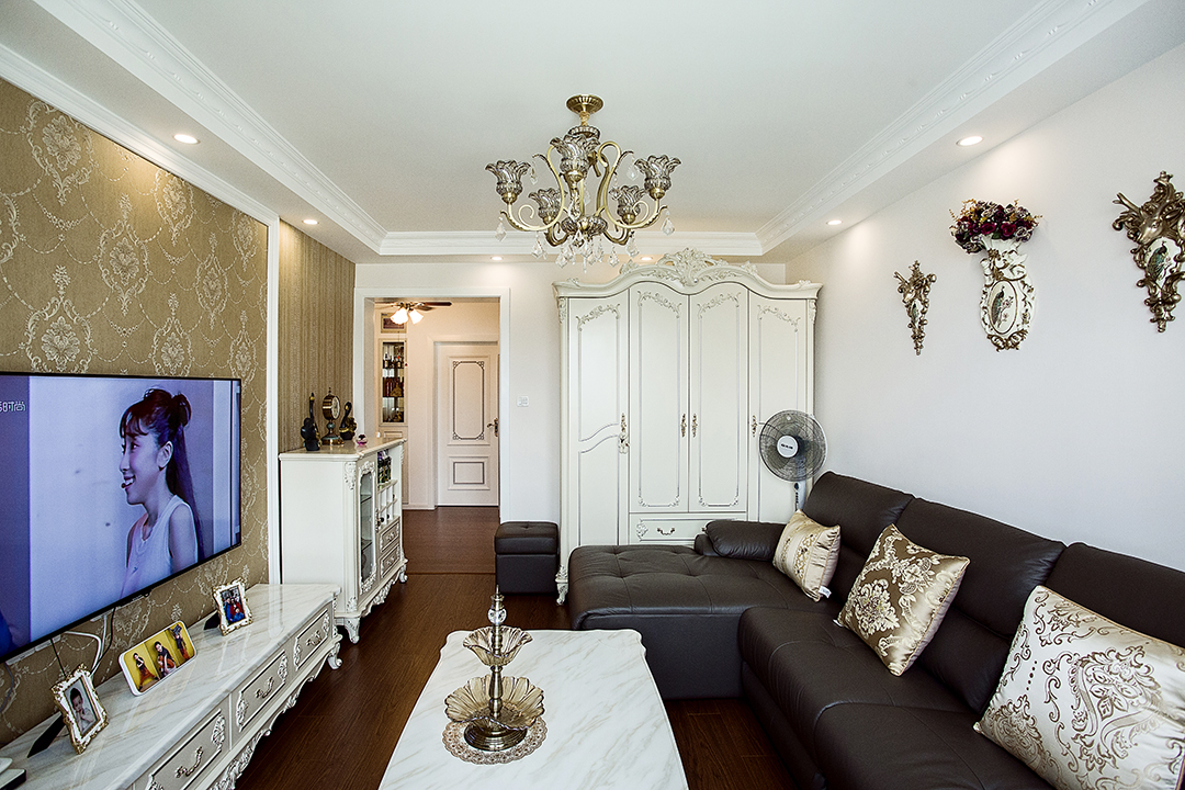 客廳采有光潔大氣的地磚，使得深色沙發不再壓抑，也更凸顯了家具的質感，品質生活油然而生。歐式家具低調而奢華，沉穩而大氣，充分體現了業主的，低調而內斂的做人風格。電視背景墻的線框采用的實木線條，中間采用的是當下比較流行的微晶石，兩邊菱形抽邊境，顯得端莊大氣。

