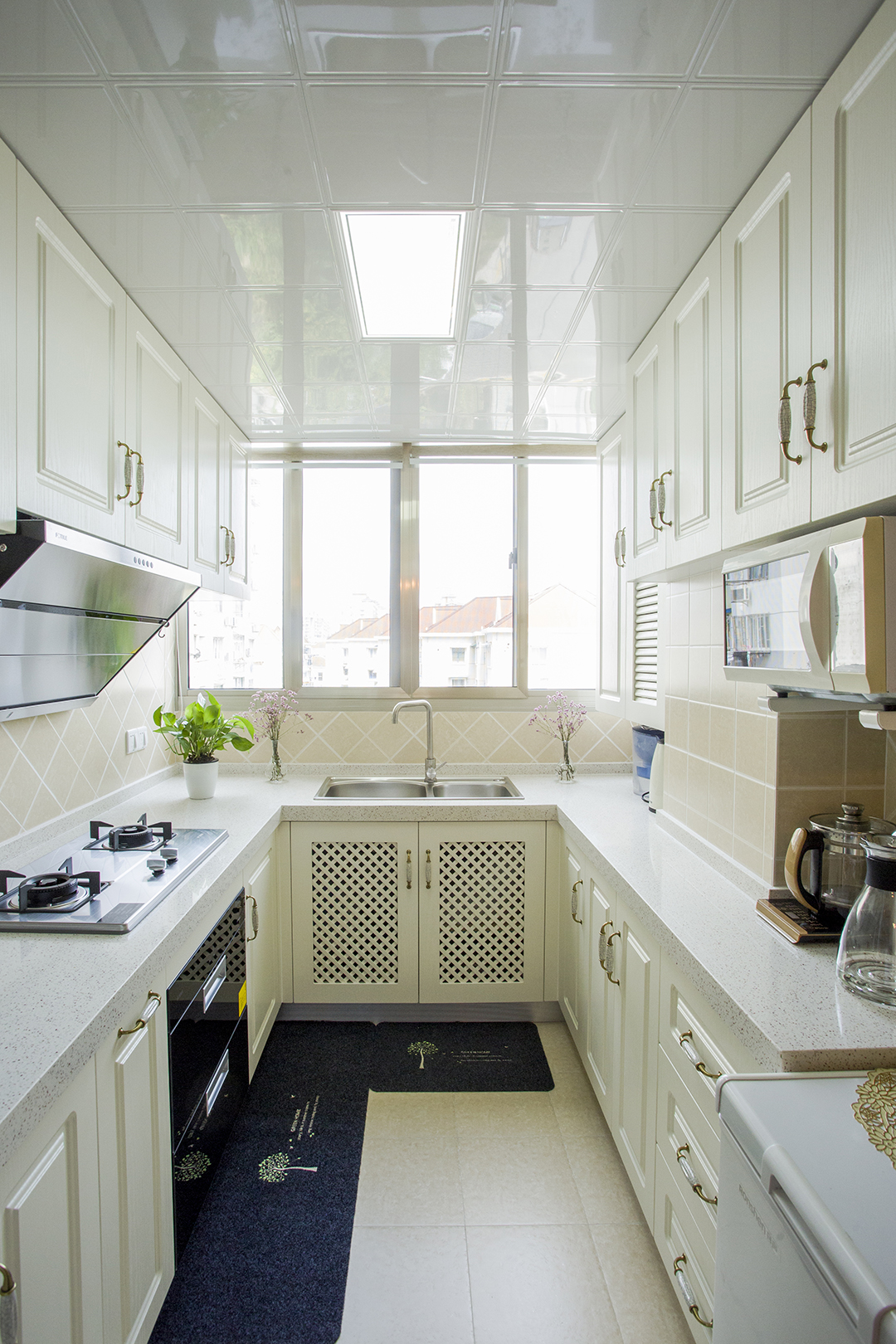 廚房間采用最簡單的歐式經典搭配，象牙白的模壓門板，再配上淺灰色的石英石臺面，堪稱是簡歐櫥柜里的最經典款。瓷磚在配上米黃色的小格子方磚，整體顏色和造型搭配上很和諧，讓整個效果看上去很有檔次。
