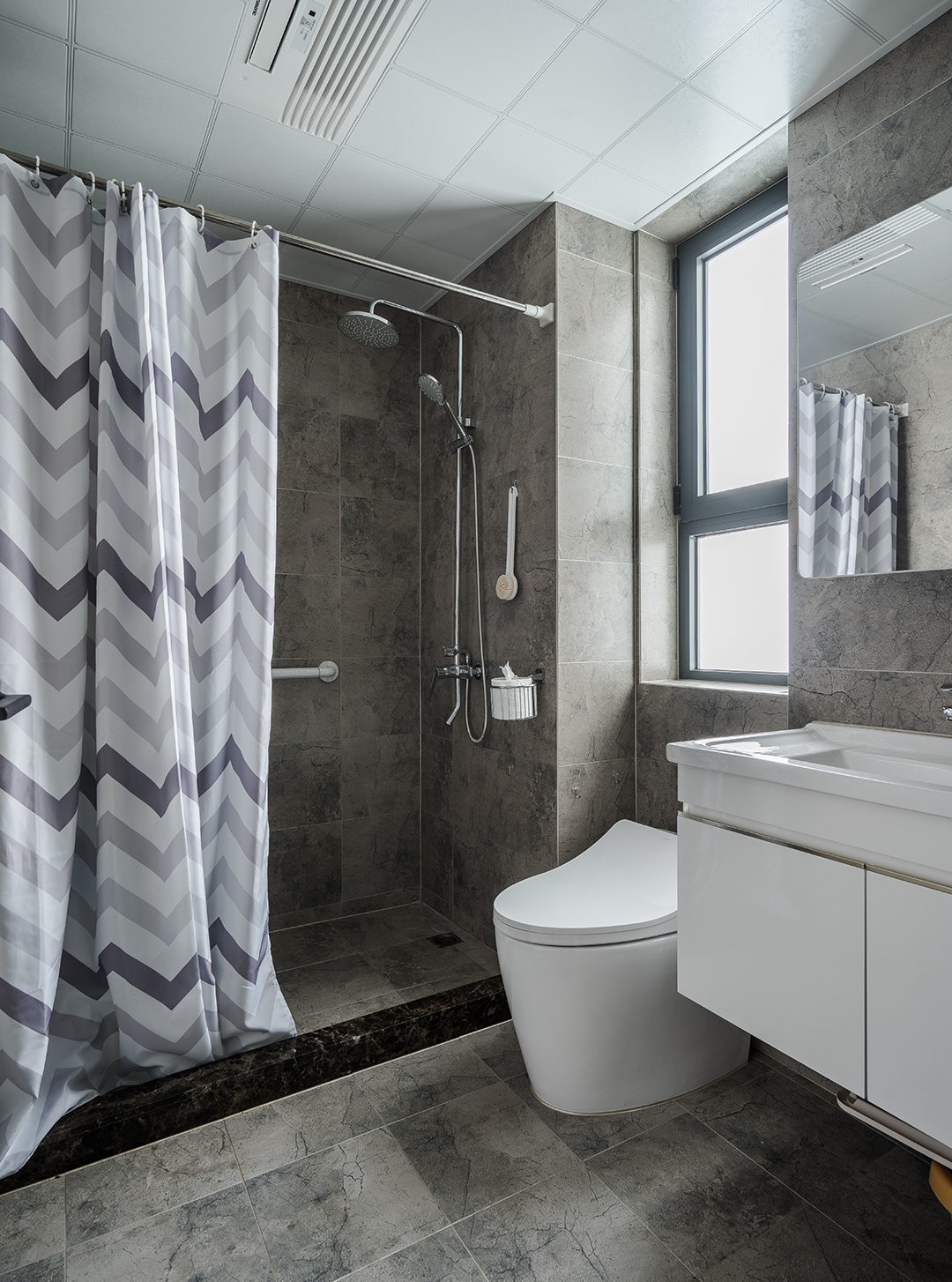 衛(wèi)生間灰色的地磚上墻，白色的衛(wèi)生潔具，給人不一樣的視覺效果。
