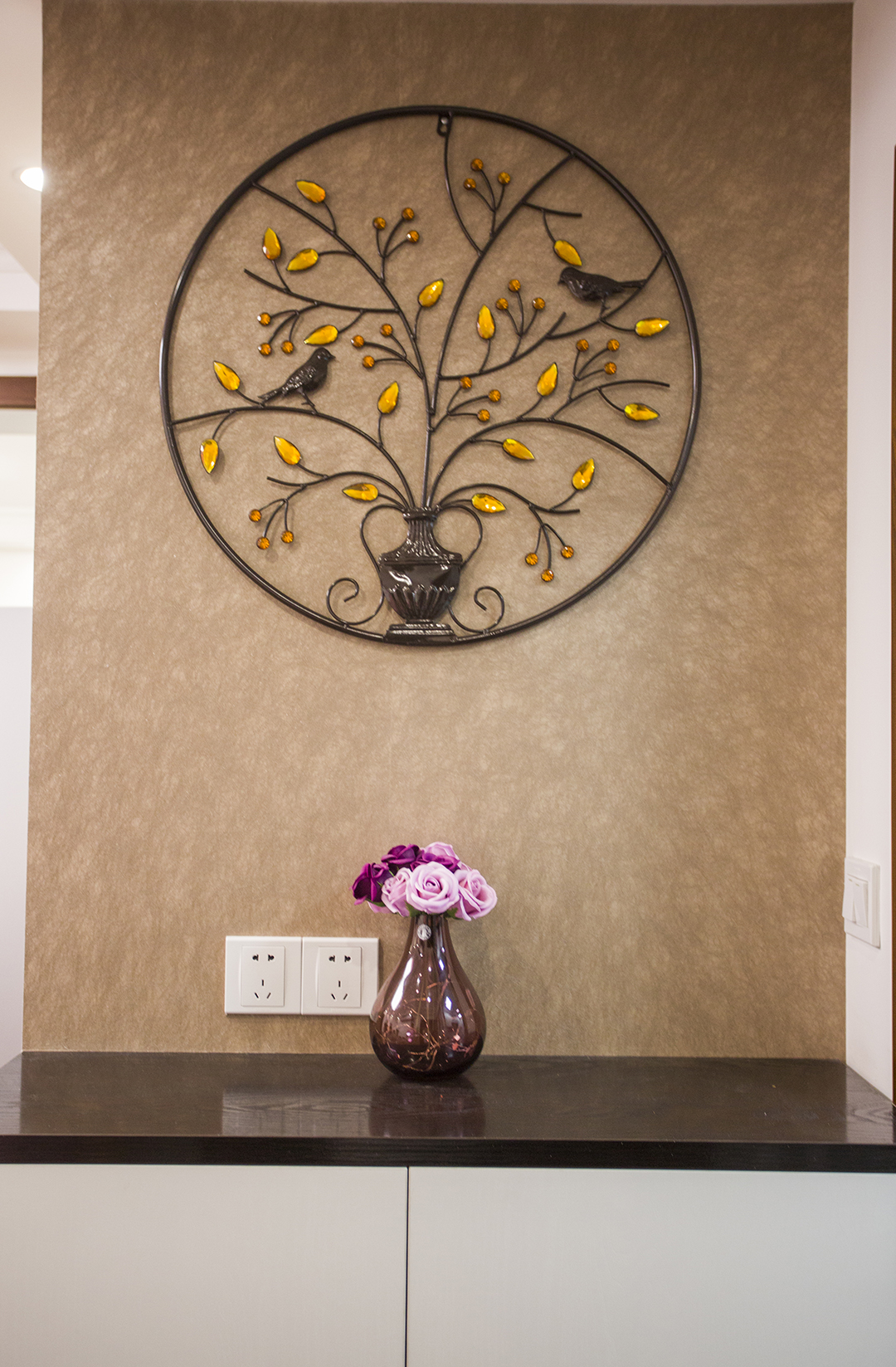 一進門的玄關是夫妻最滿意的一點，一是區分了室內外空間，做到了室內外的分割，讓小戶型也有了大戶型的莊重感，深色壁紙配上純白色柜子，大方的同時不失輕快.墻面鐵藝工藝品更是畫龍點睛的突出了主人低調奢華的品味.