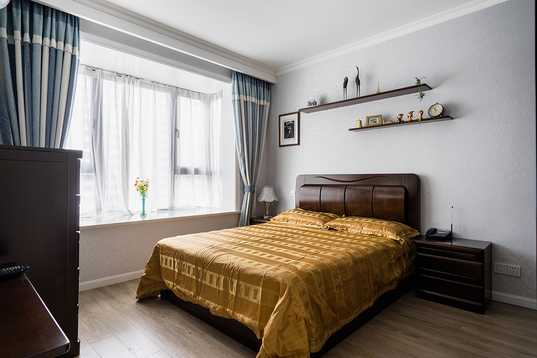 臥室的大飄窗將室外美景盡收眼底，設(shè)計上盡量保持空間簡約，注重以墻面裝飾來彰顯格調(diào)，床頭實木隔板，構(gòu)筑時尚氣息和多層次視覺。
