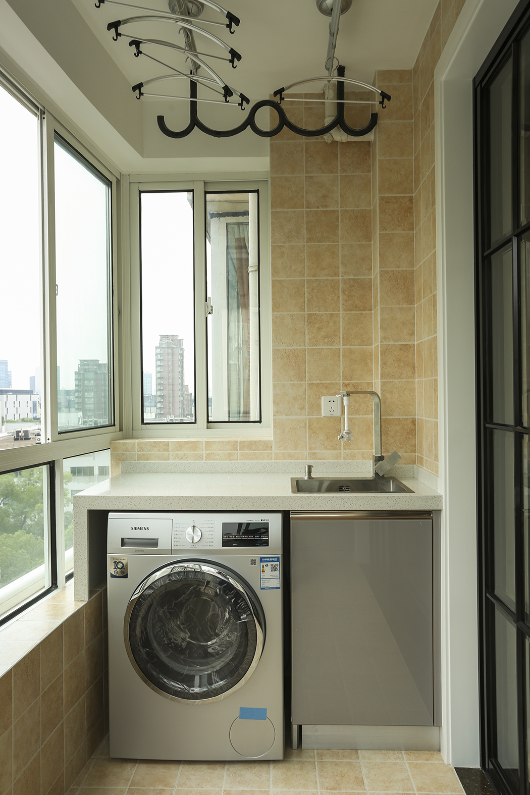 陽臺的瓷磚選擇了仿古亞光面的感覺，讓陽臺成為了一個休閑工作的空間，定制的洗衣機一體柜讓空間擺放更加的合情合理。
