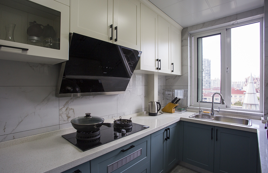廚房間選擇大理石的?；u，再配上模壓門板的櫥柜，上柜以現(xiàn)代簡約里最常見的象牙白為主，下柜以湖藍色的線條門板為主，黑色的門把鎖格外顯眼，起了一定的點綴和裝飾作用，讓整個廚房間更加和諧、時尚。
