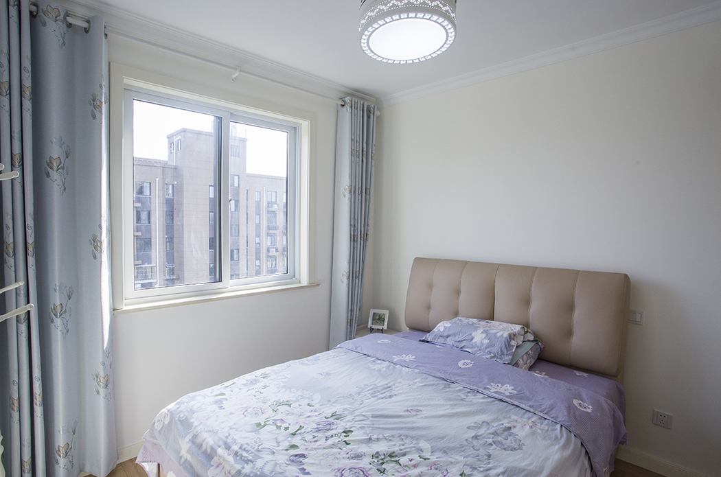 主臥鵝黃色的墻面在陽光明媚的下午顯得靜謐而淡雅，紫色的花藝床品配上床頭的軟包，溫馨又溫暖。
