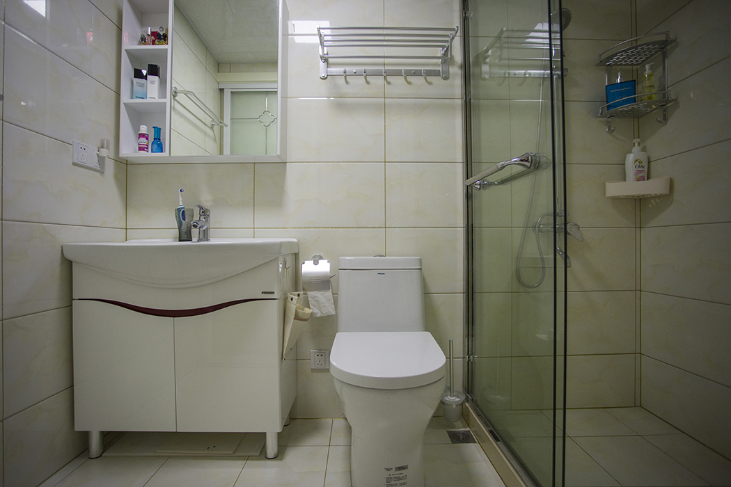 縮小面積之后的衛(wèi)生間剛剛好擺放臺盆、坐便器、淋浴間“三大件”，明亮整潔。門洞改到中間后，避免了直對進戶門的“門沖”。
