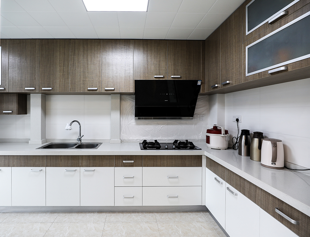 廚房擴大了面積，將原先的北陽臺融入其中，把做飯變成了一件賞心悅目的事情。造型簡潔的瓷磚墻面淺木紋的櫥柜形成一抹天然粗獷的風格
