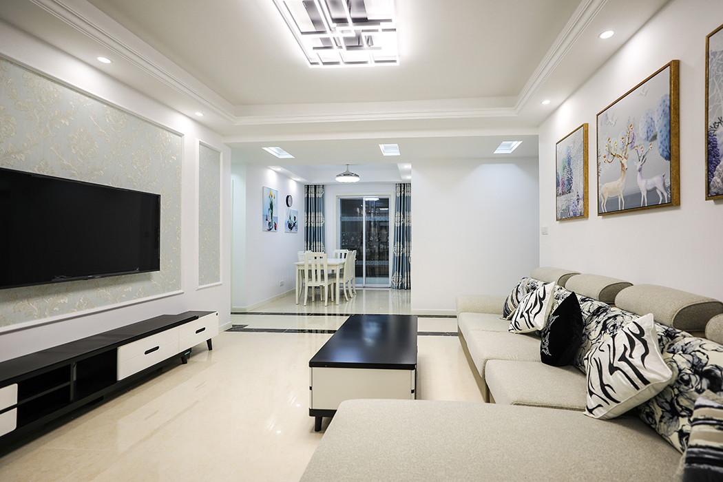 沙發背景的三幅色彩豐富的裝飾掛畫一下子把整個客廳氛圍活躍起來了，而且和電視背景的三個石膏線造型方框相呼應，電視背景墻以石膏線方框和墻紙組合，造型上凸現了簡歐風格的大氣尊貴和時尚經典。墻紙顏色上以淺藍底色印金色花紋和金色的畫框相協調，詮釋了現代簡歐風的雍容華貴。
