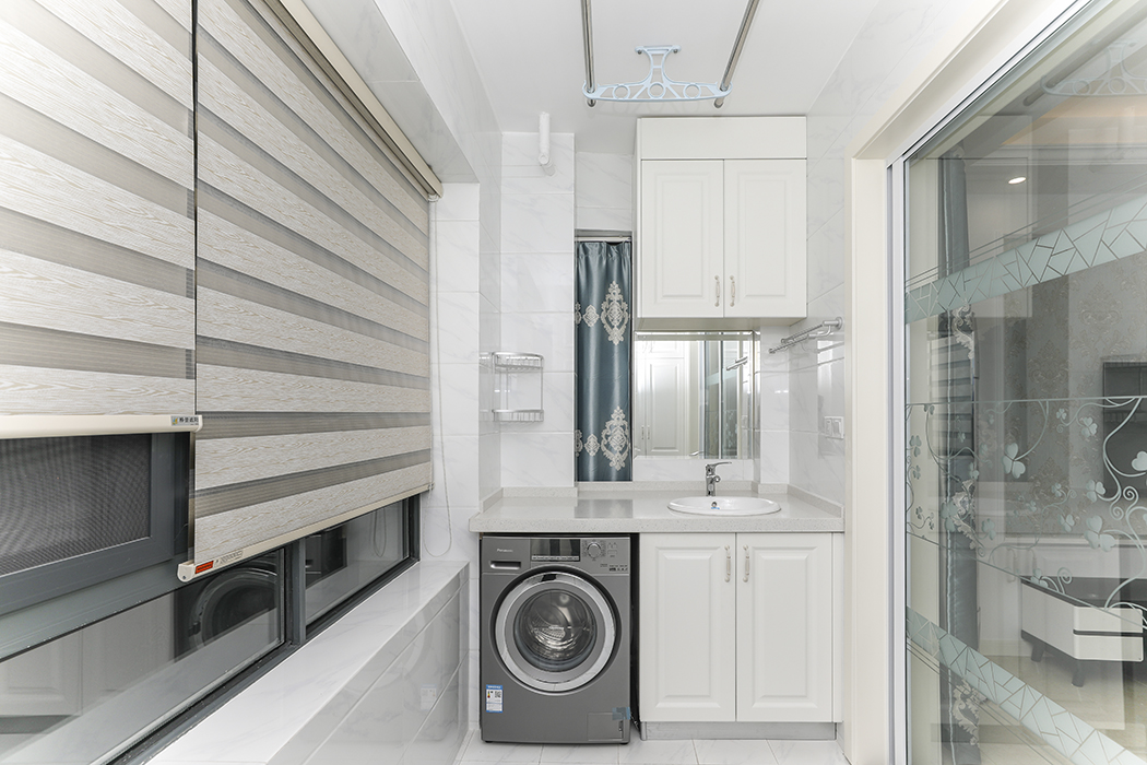 陽臺是建筑物室內的延伸，是居住者呼吸新鮮空氣、晾曬衣物、擺放盆栽的場所，其設計需要兼顧實用與美觀的原則。1.5米寬的大陽臺解決了本套房子只有一個衛生間的不足，陽臺的一面配上鏡子、毛巾架和肥皂盒，不僅可以當做洗衣區，還可以當做洗漱區，顏色以白色為主，既干凈清爽，又簡潔大方，上下柜子滿足了主人的收納需求。
