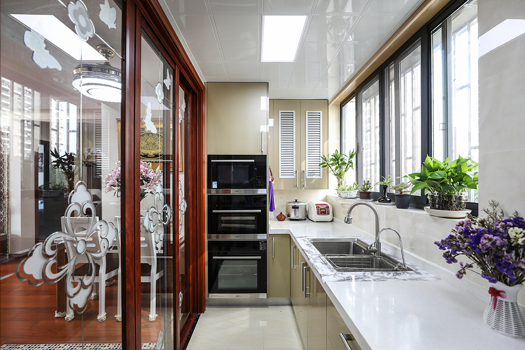 廚房間的設計風格并沒有沿用整體的新中式的理念，而是采用了更加直接實用的亞克力作為主體，簡約的同時又便于打理。白色的瓷磚搭配香檳色的櫥柜，凸顯了更多的層次。
