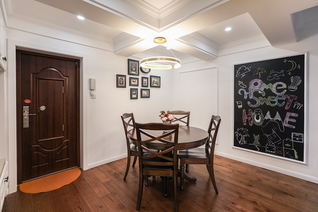 餐廳吊頂采用9宮格式吊頂，把原先的大梁弱化，配上石膏線條，搭配上實(shí)木餐桌，美式風(fēng)格元素盡顯。餐桌旁墻面黑板漆盡顯童趣，小朋友可以隨時(shí)涂鴉，增加趣味性。
