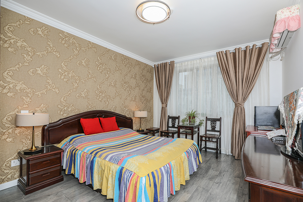 主臥是人到中年的業主夫妻住，要搭配原來保留的一套家具，所以選擇了中式風格，雖然地板統一用了灰色調，但是增加了中式風格的墻布當床背景，加上原有中式的家具和窗簾，讓這個房間和外面的客餐廳成了鮮明的對比。
