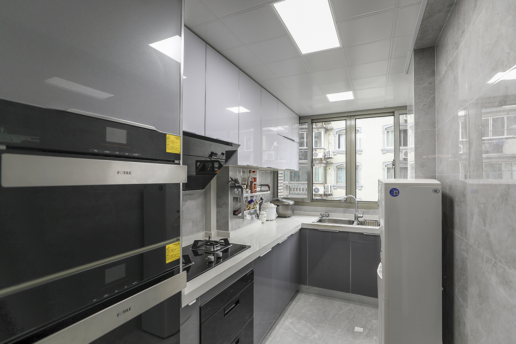 廚房間還是一如既往的灰色調，原本非常的狹長，后期把廚房縮小了一部分，把冰箱和儲物柜融入一體放置廚房外，為了后期使用方便加了高柜來放置烤箱和蒸箱。
