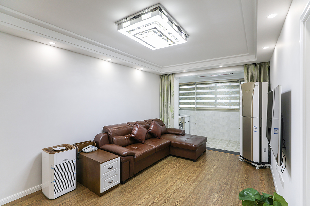 客廳整體風(fēng)格采用灰色墻面涂料和灰色木紋系的地板合理搭配，沙發(fā)采用以皮色棕色為基礎(chǔ)的色彩搭配，使得整體空間的延伸，吊頂采用臺階式吊頂加以簡單線條，配以中性色的射燈，使得光線得以明朗，視覺得以解放。
