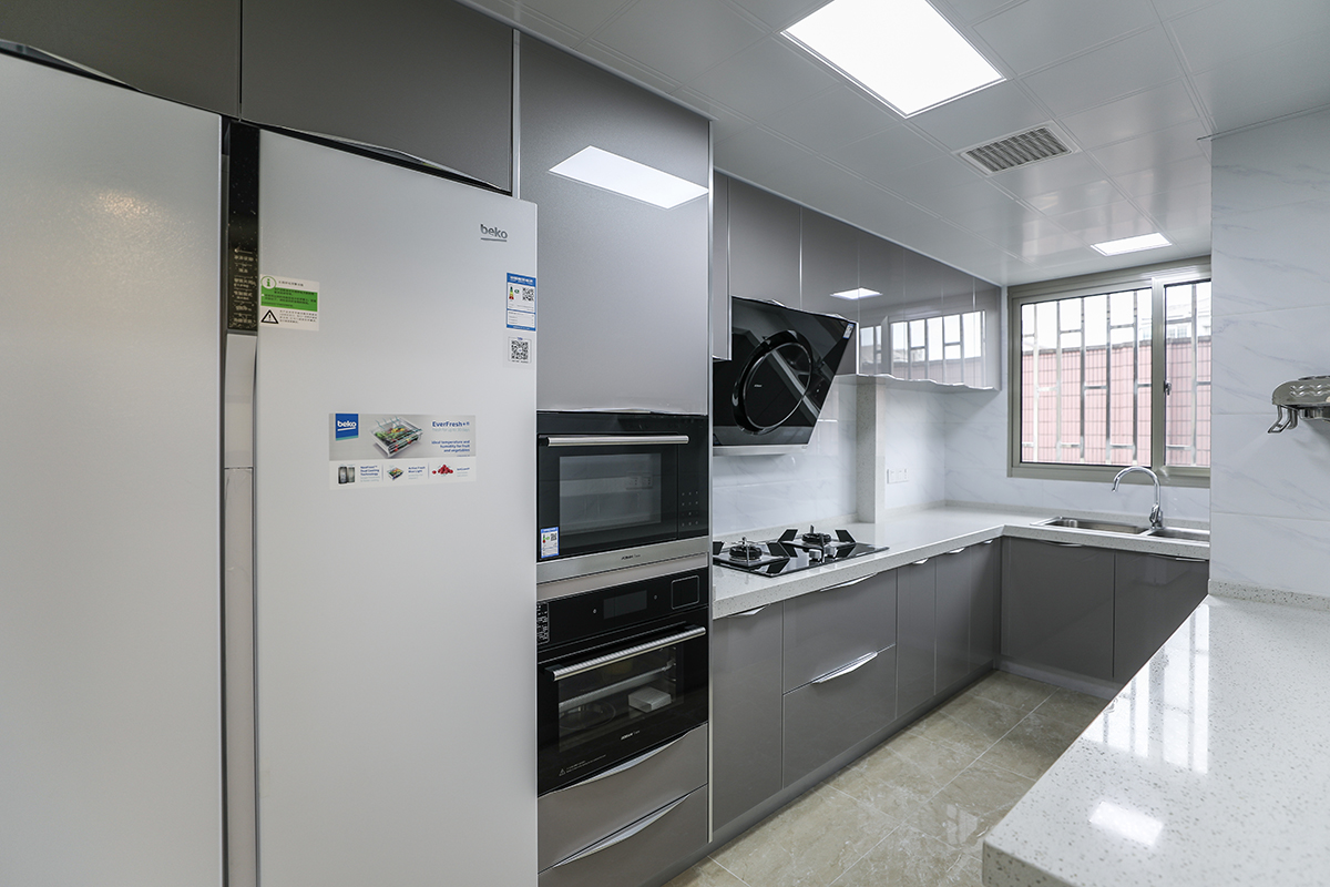 廚房采用灰色色系，充分體現(xiàn)簡約風(fēng)格，側(cè)吸的煙機(jī)，白色臺面和灰色櫥柜的合理搭配，顯現(xiàn)出客戶的整潔生活，灰色和白色瓷磚的搭配更加的合理大氣，隨著家庭電器的不斷增加使得廚房在設(shè)計(jì)上對于電器的需求充分合理的安排。
