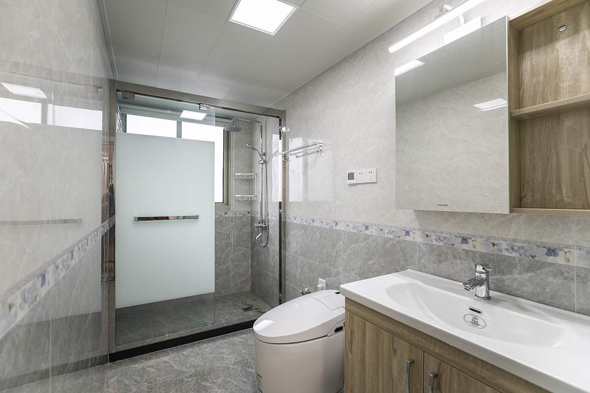 這個(gè)衛(wèi)生間整體格局非常的不錯(cuò)，所以在墻面瓷磚上的運(yùn)用采用了上磚+腰帶+下磚的風(fēng)格搭配，主要以灰色系為主，配以紫羅蘭的腰帶色彩，使得整體的色彩非常的舒適協(xié)調(diào)。
