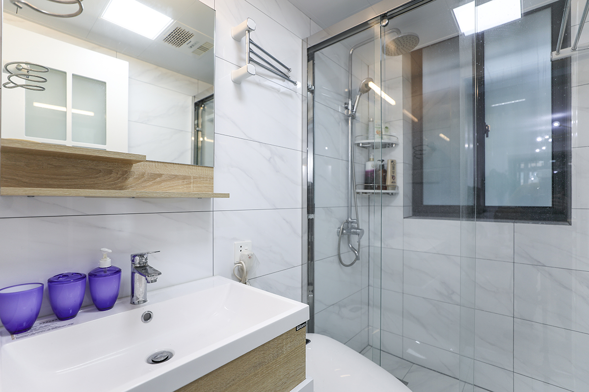 衛(wèi)生間以實用為主，一般分為三大功能區(qū)，盥洗區(qū)、廁所區(qū)、浴室區(qū)。盥洗在前，廁所居中，浴室在后。該空間各大功能區(qū)布置的井井有條，色調(diào)上白色的潔具、白色的瓷地磚配上暖色調(diào)的實木浴室柜，使衛(wèi)生間既干凈又溫馨。