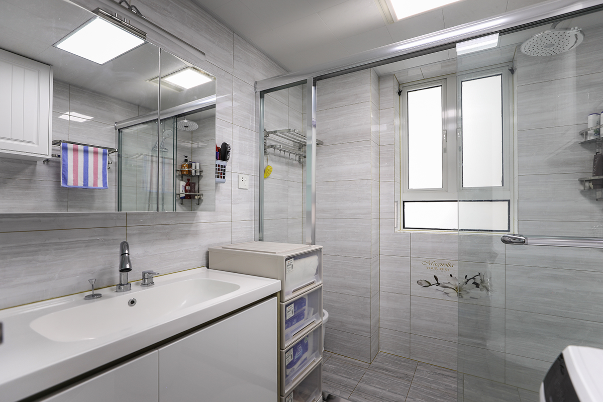 白色總是可以讓人的心情放松，小戶型的衛(wèi)生間淡灰色色的瓷磚，可以讓空間看起來寬闊明亮，空間大了，心自然就開闊了。淋浴房用玻璃隔斷起來，不僅增加整個(gè)衛(wèi)生間的美感，同時(shí)防止衣服被沐浴的水打濕。
