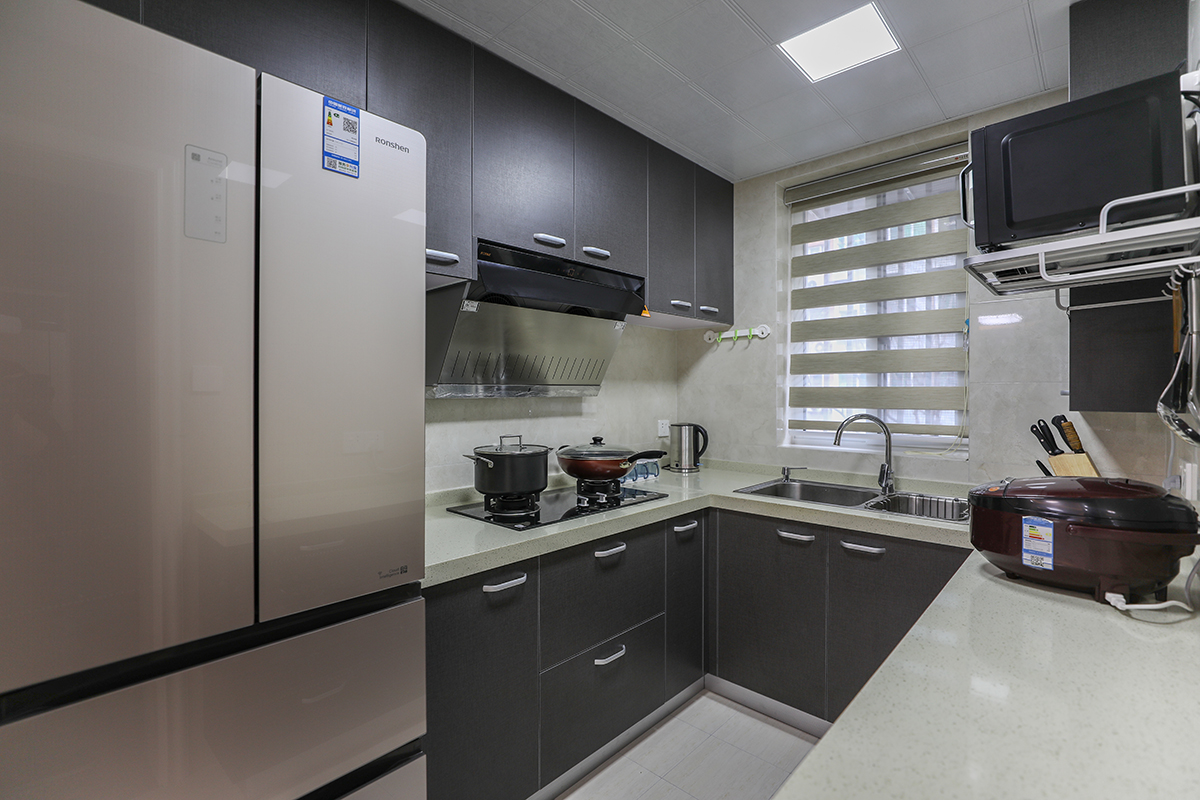 廚房設計成U形廚房，擴大了進門的視覺空間，又使得廚房的操作和儲物成倍的提升。整個顏色以黑白灰為主。
