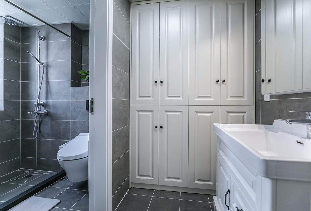 衛(wèi)生間采用干濕分離，日常使用更加方便。干區(qū)除了臺盆柜，也根據(jù)主人的生活習慣，設計放置了一面儲物柜。灰色亞光仿古磚，與整體色調風格統(tǒng)一和諧。 
