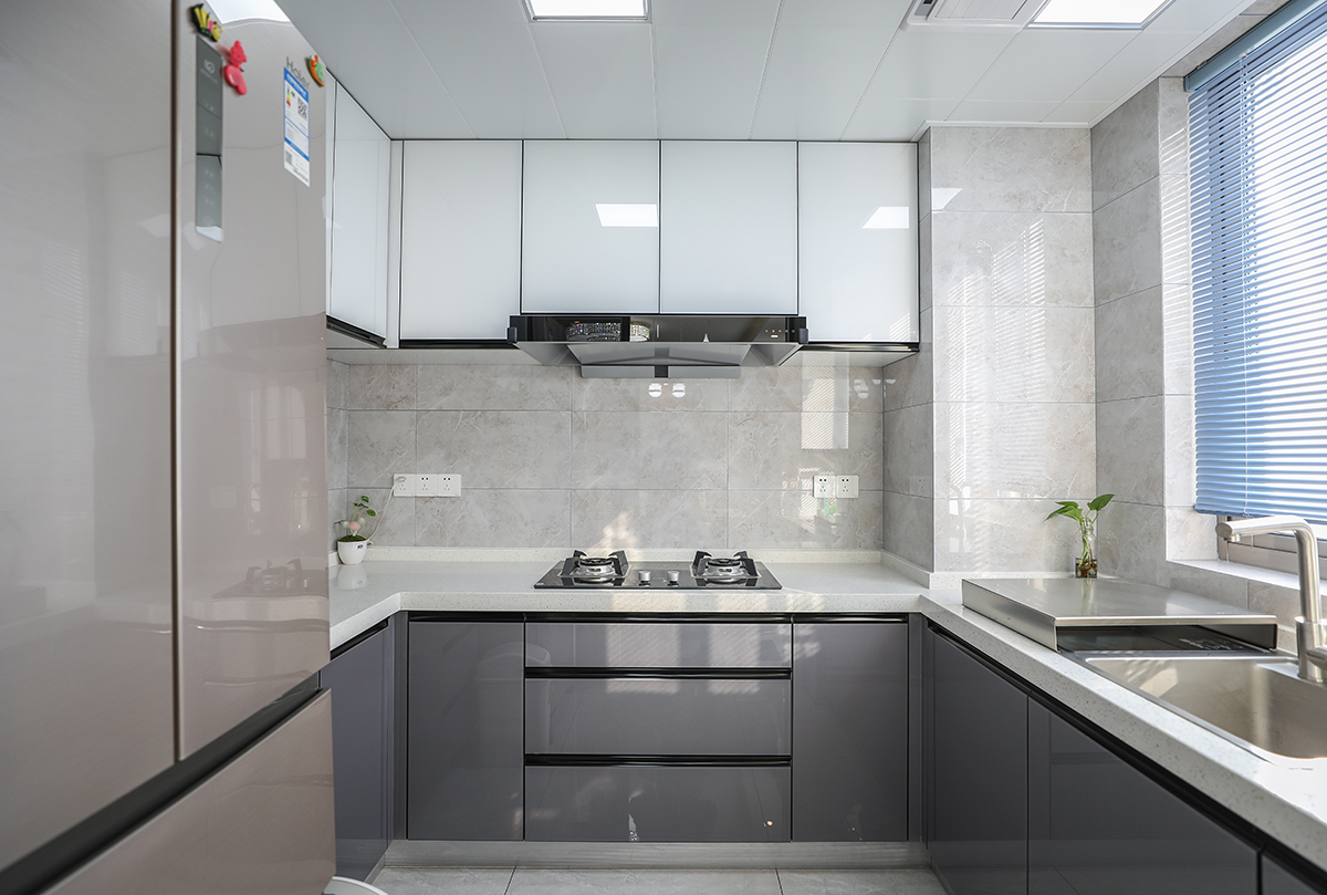 廚房選用晶鋼板櫥柜，上柜及下柜做拼色處理，配色穩重又不顯得昏暗，吊柜及臺面選用白色黑色隱形把手，墻面瓷磚偏灰，黑白灰的搭配既簡潔又有層次。
