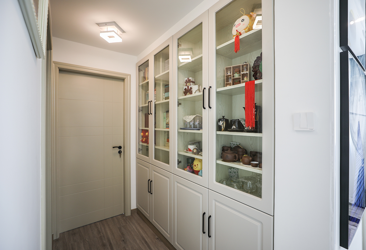 過道儲物門板上柜玻璃使得原本狹窄的過道更有深度，不僅起到了隔斷的作用同時讓空間有足夠的儲物及展示空間。
