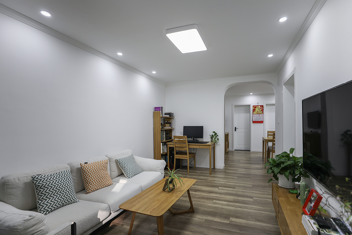 客廳仍然以白色為主色調(diào)，通過(guò)原木色的融入以及灰色的過(guò)渡，呈現(xiàn)簡(jiǎn)潔明快的生活氣息，橢圓形拱門的設(shè)計(jì)增添了些許俏皮。
