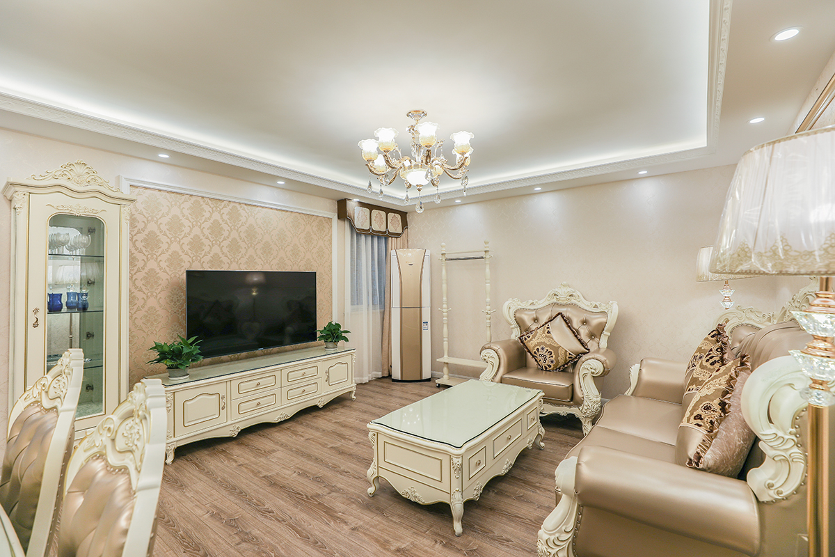 客廳的玻璃窗帶來了良好的采光，落地的窗簾很是氣派。布藝沙發組合有著絲絨的質感以及流暢的木質曲線，將傳統歐式家居的奢華與現代家居的實用性完美地結合。壁爐自然不可或缺，它被安置在空間結構的交匯處，與一幅色彩鮮艷的油畫相呼應，敞開式的客廳提供了一個視覺中心。
