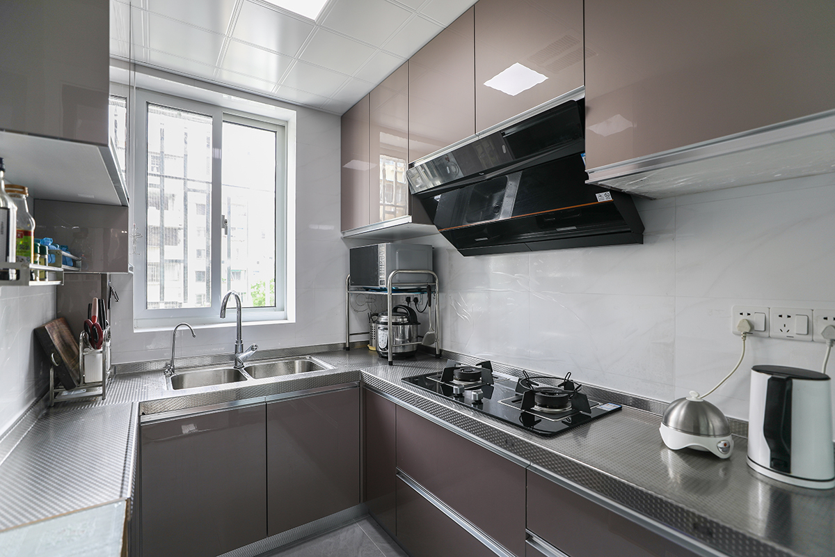 廚房是使用頻率最高的區域，不但要功能齊全，又要方便清潔好打理，所以材質上采用金鋼門板，考濾臺面要經久耐用，所以彩用不銹鋼臺面，配上白色大理石紋理墻磚、金色櫥柜門板。空間簡潔、干凈，方便清理，色調上又不單一。
