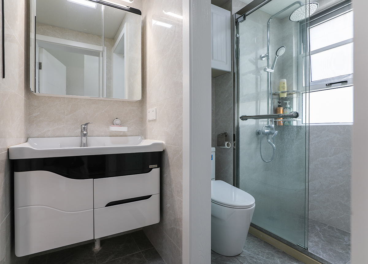 衛生間的主色調為淺咖色，墻壁四周和地面都鋪了淺咖色瓷磚，典型的現代風格，面盆的設計讓使用更加方便，淋浴的位置靠窗，淋浴房與馬桶側做了干濕分離的設計，保證了動線的流暢也不影響洗漱和馬桶區域的視野。
